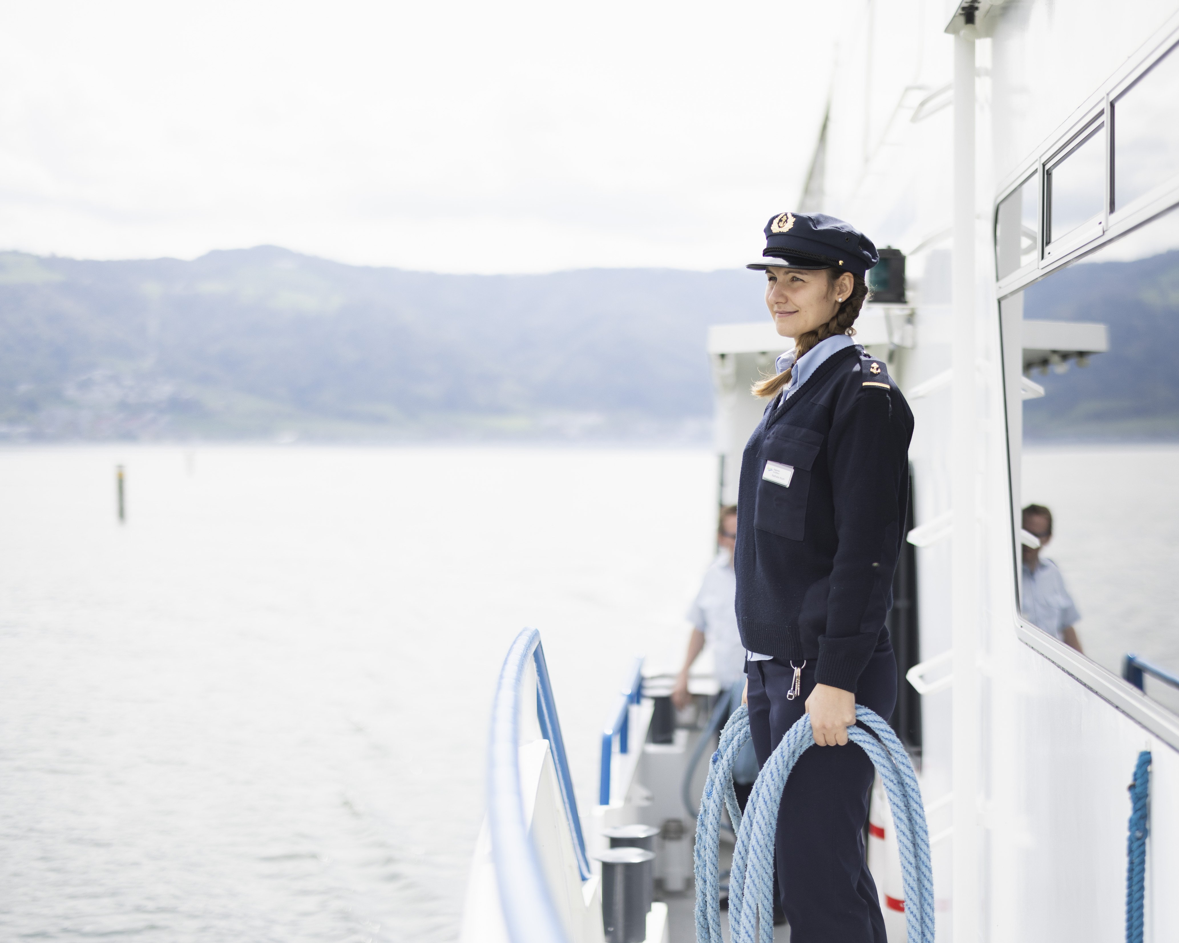 Sailor standing at the railing with a rope in her hand