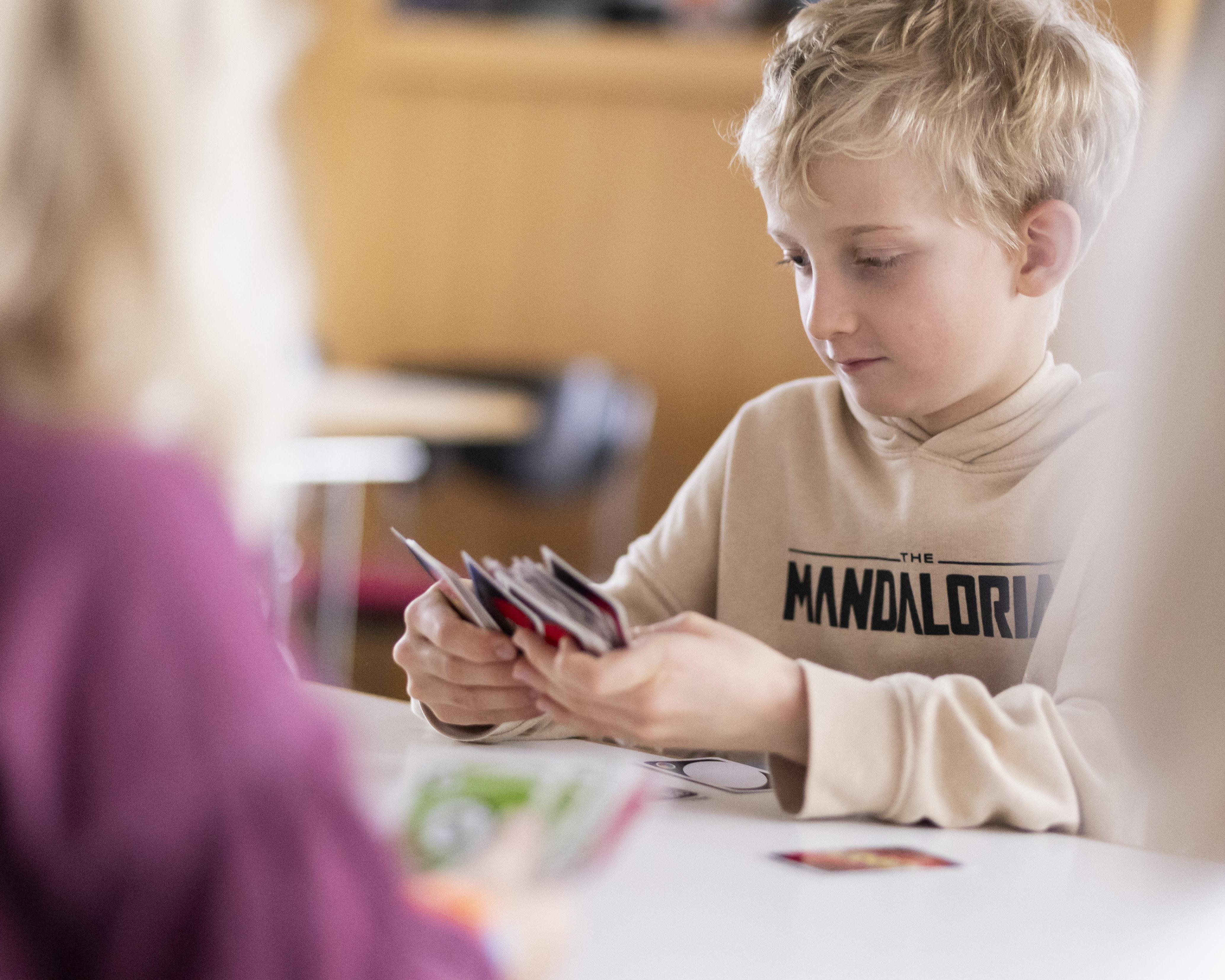 Junge spielt Uno am Tisch