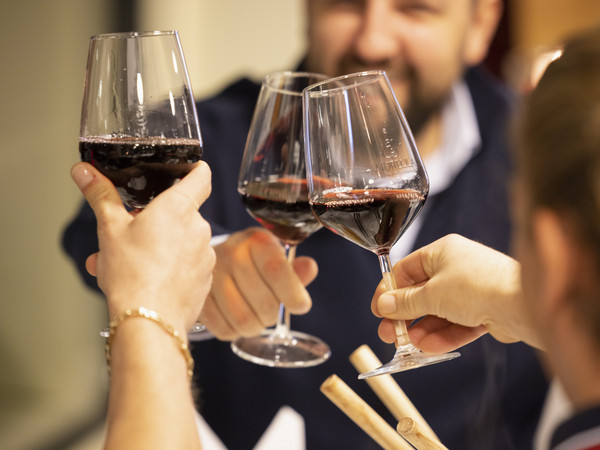Three guests toast with glasses of red wine