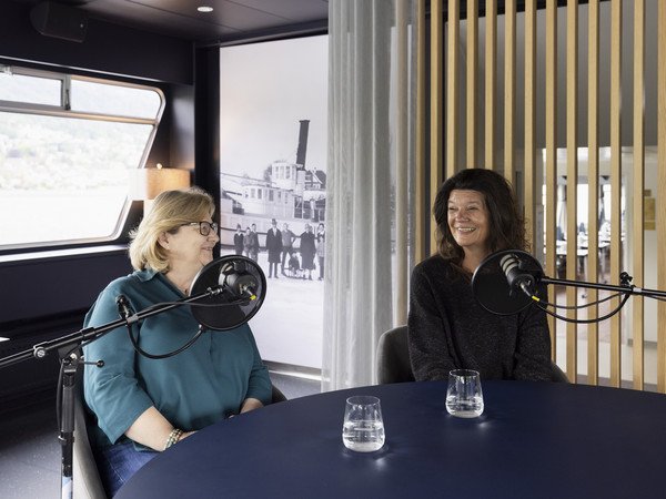 Monique und Carmela zusammen am Podcasttisch vor dem Mikrophon