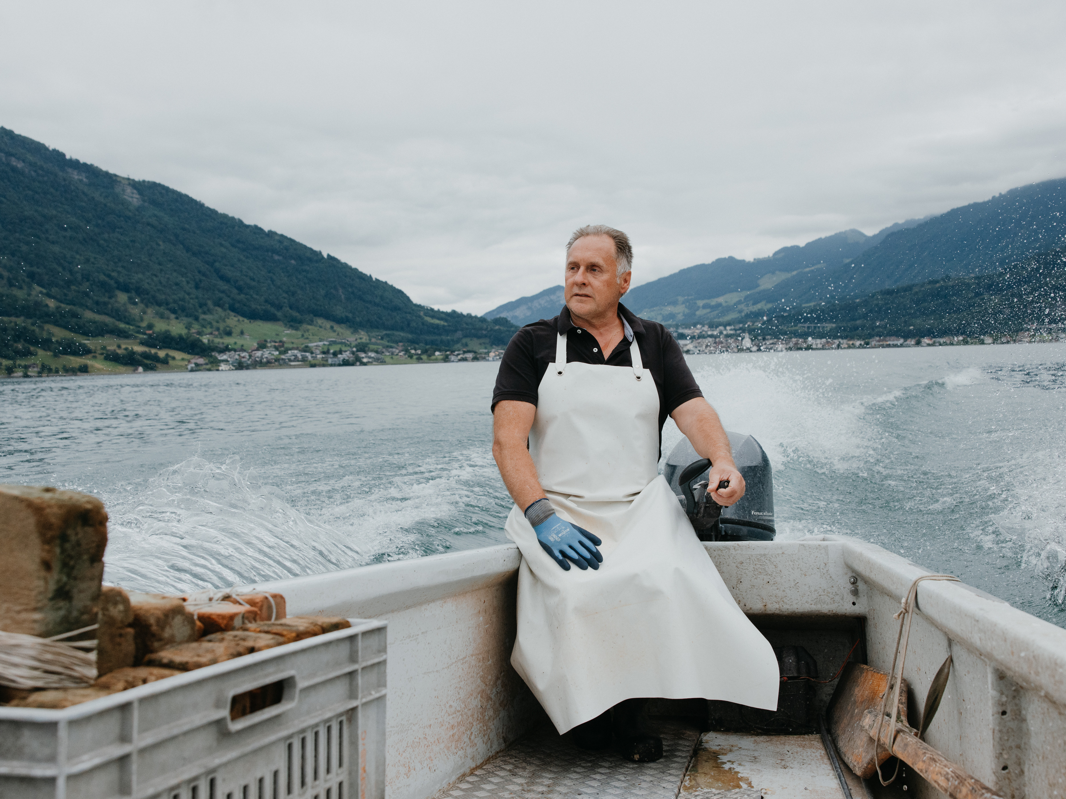 Fisherman Daniel Schwendeler steers fishing boat on the lake