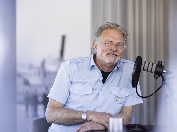 Porträt Kapitän Benj Schacht vor dem Podcast Mikrophon