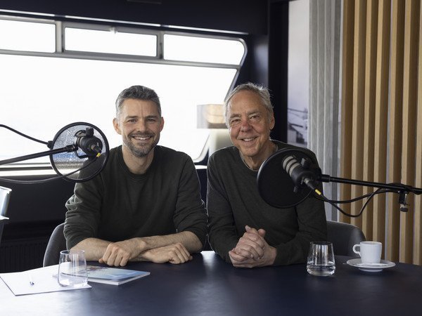 Podcast Gäste Ivan Steiner und Urs Eberhard sitzen am Tisch vor den Mikrophonen