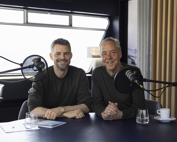 Podcast Gäste Ivan Steiner und Urs Eberhard sitzen am Tisch vor den Mikrophonen