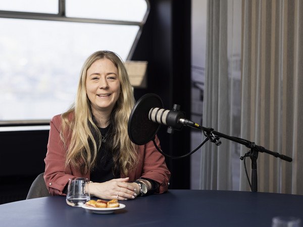 Simone Glarner am Podcasttisch neben Mikrophon sitzend