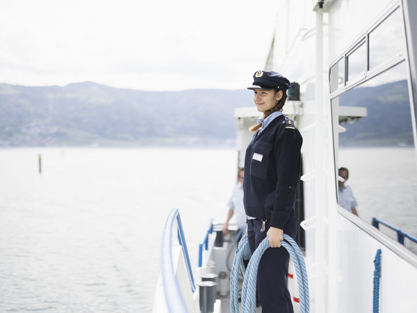 Matrosin steht an Reling mit Seil in der Hand
