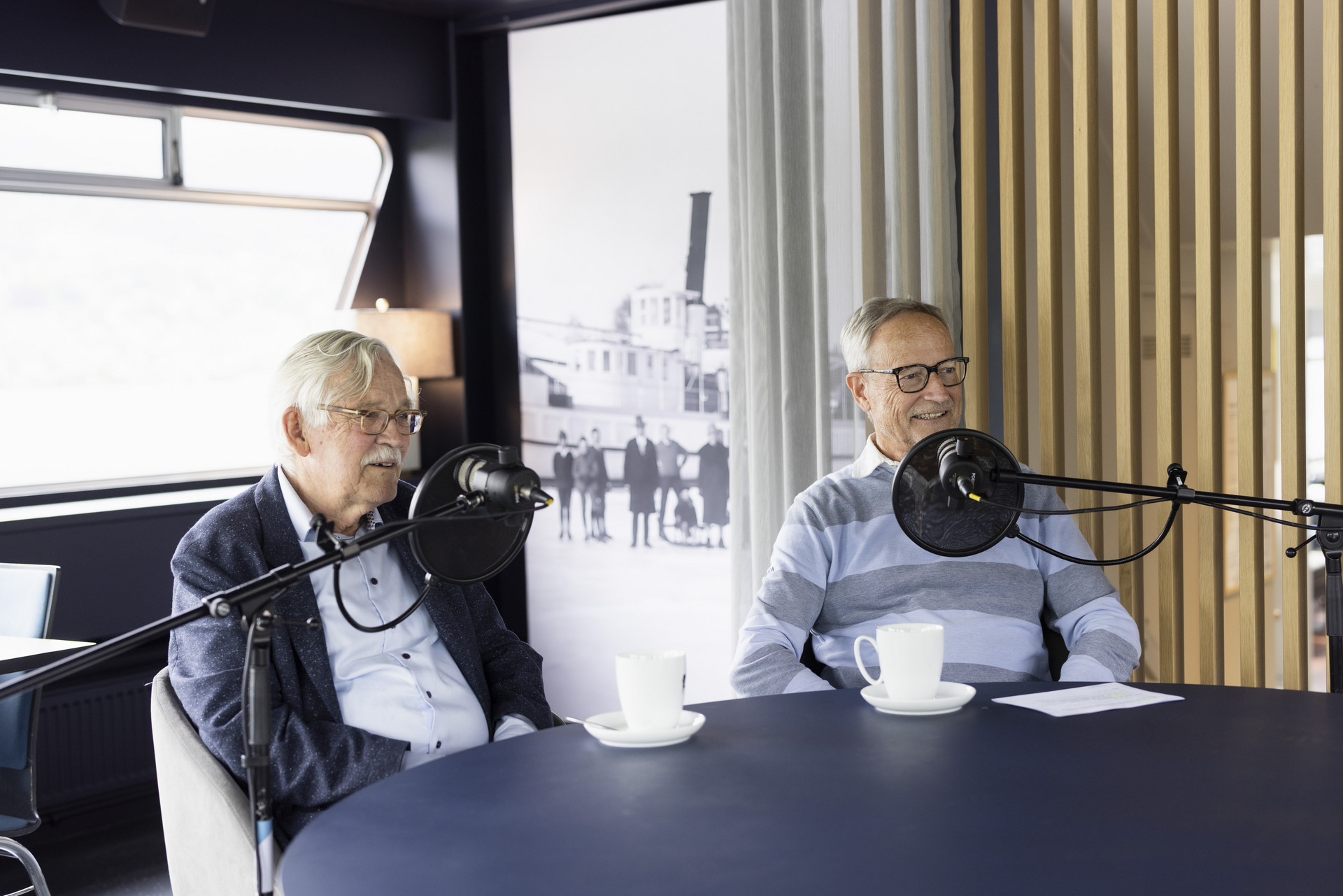 Heinz Amstad und Jürg Meister während der Podcastaufnahme am Tisch sitzend