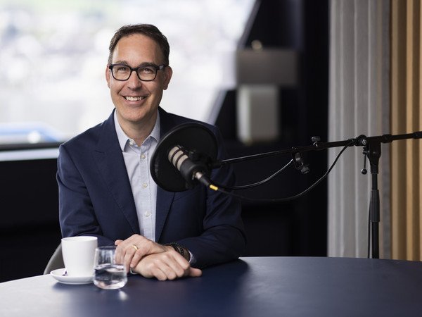 Remo Rey vor dem Podcast Mikrophon mit Kaffeetasse