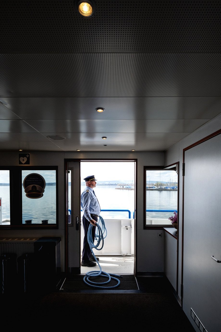 Schiffsführer steht an Reeling mit Seil in der Hand Schiffsführer im Türrahmen stehend an Reeling mit Seil in der Hand