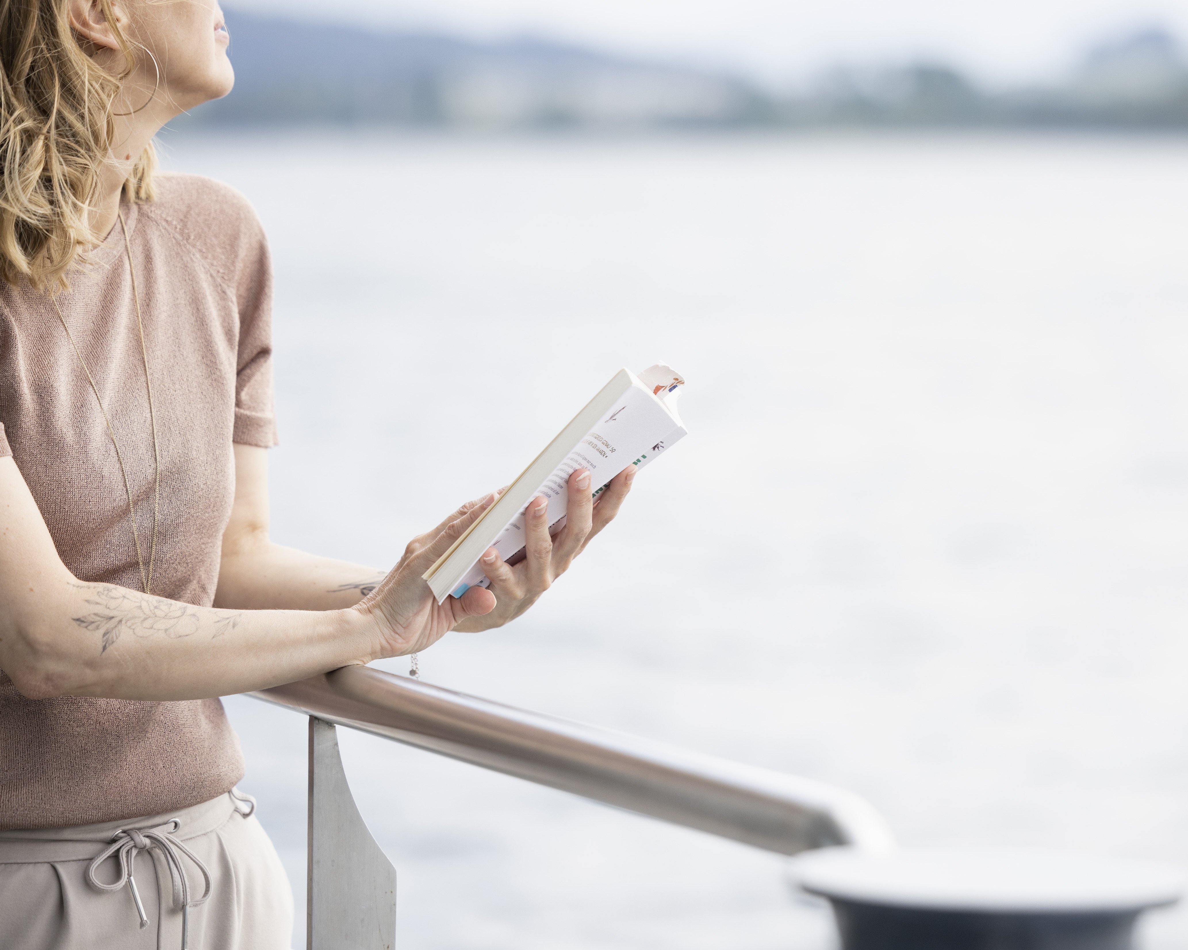 Woman reading at the railing with a view of the lake