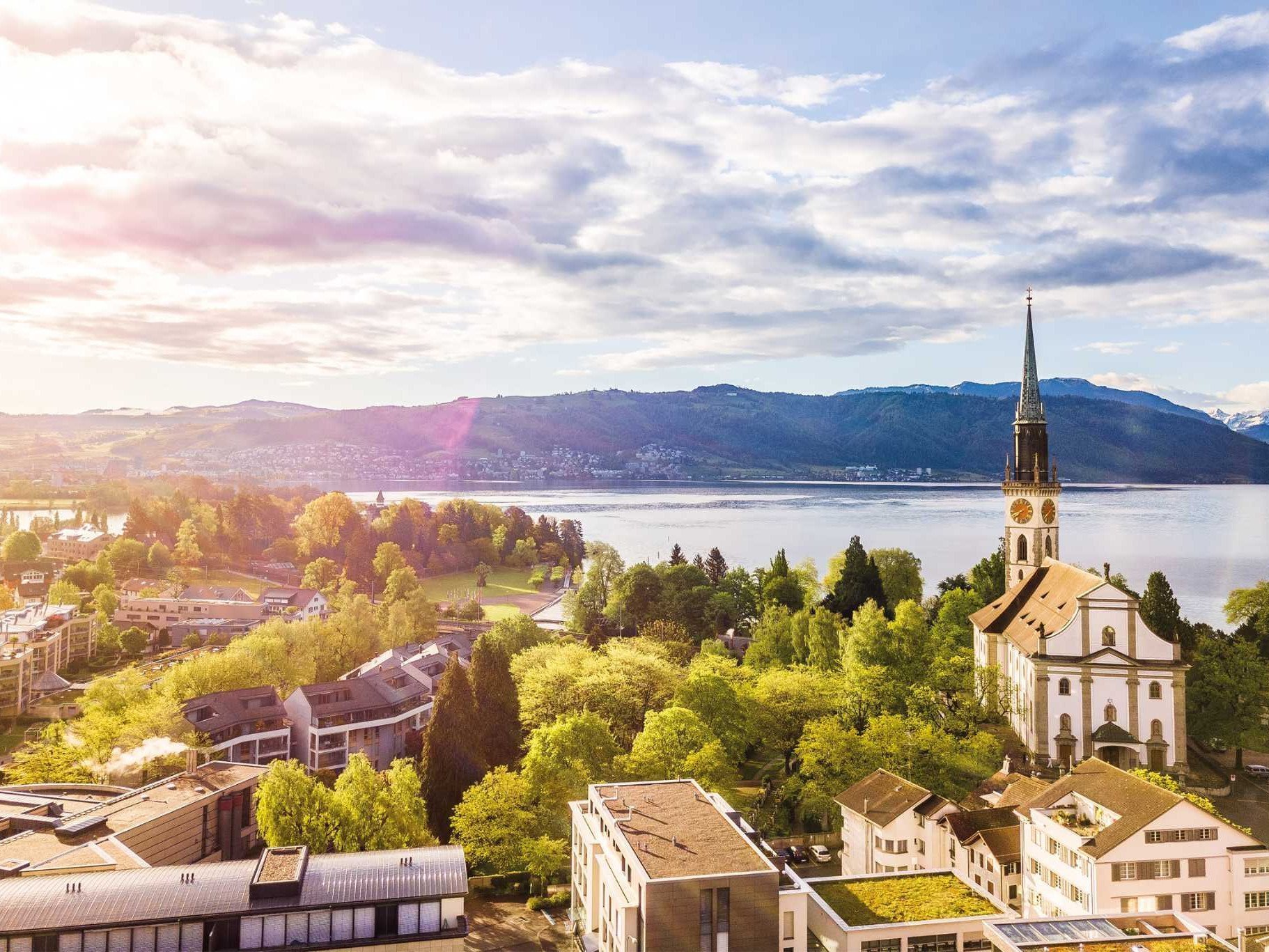 Flugaufnahme von Cham mit Kirchenturm und Zugersee im Hintergrund