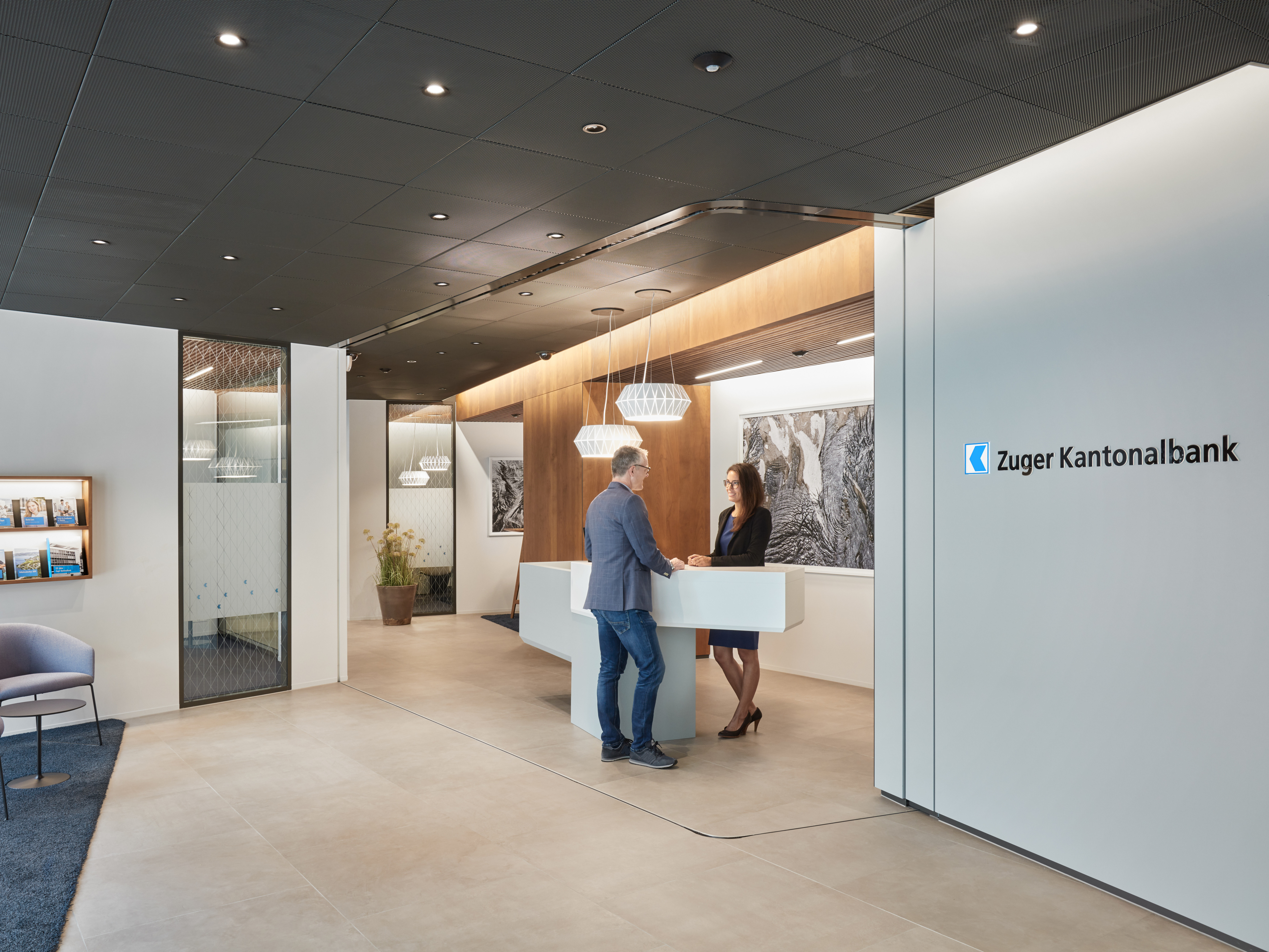 Man stands with woman at the counter in a branch of Zuger Kantonalbank