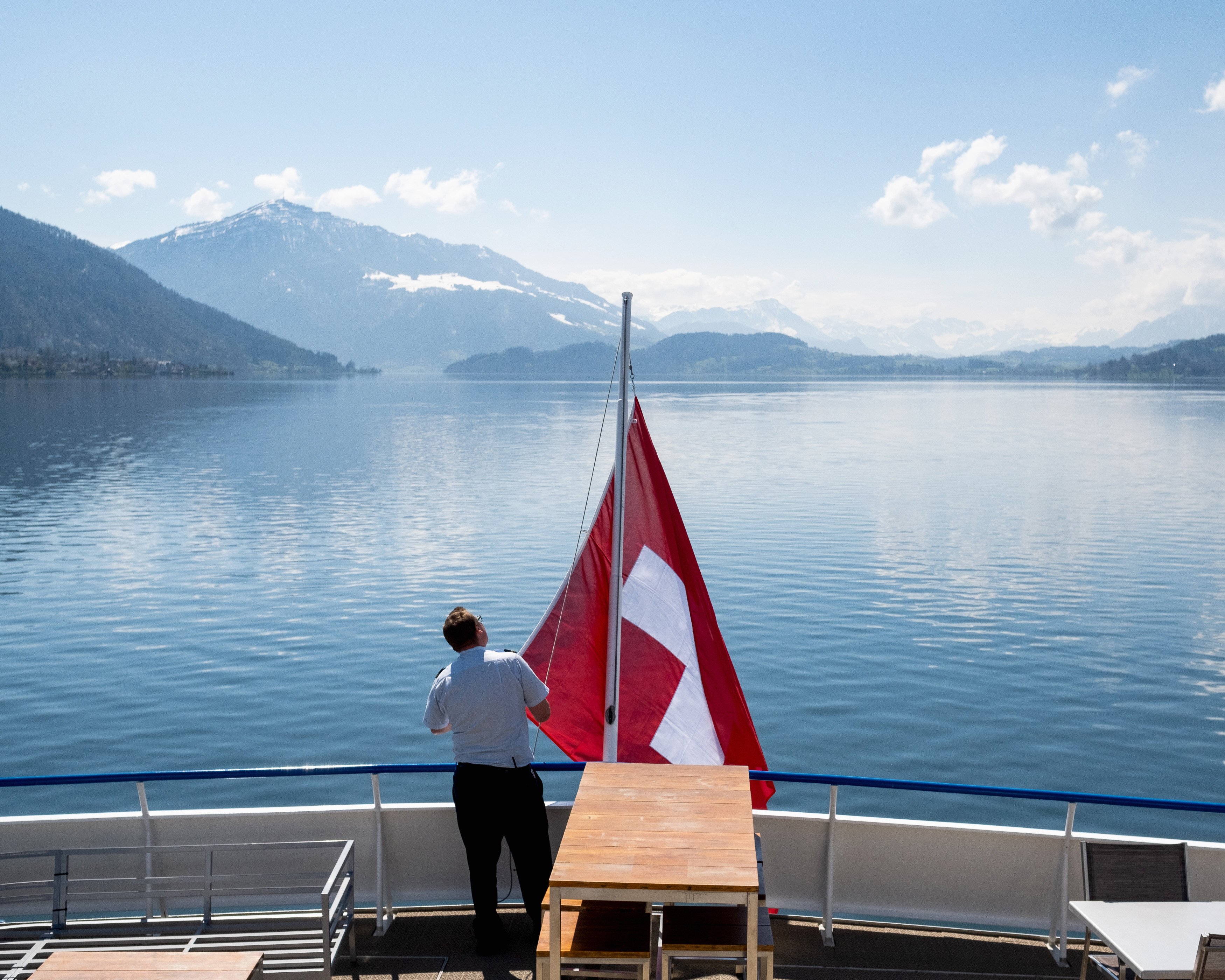 Matrose hisst die Schweizerflagge auf dem Heck mit Blick auf den See