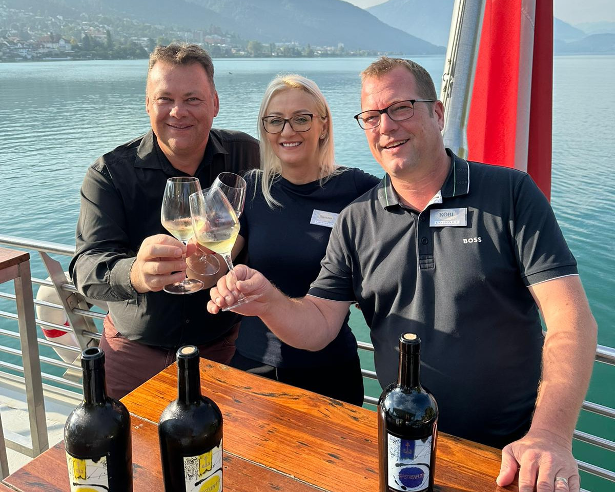 Three people toast with Gastronautic wine, with the lake in the background